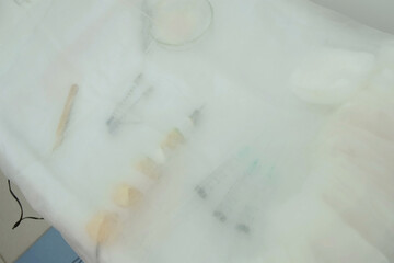 Preparation of operating room for surgeon operation in hospital. Instruments are laid out on table covered with white sterile cloth. Prepared tools, injections, machine to surgery practice in clinic.