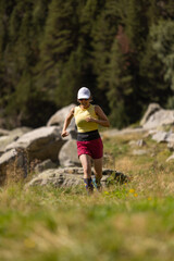 A woman is running in a field with a hat on