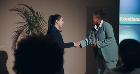 Business women, handshake and smile for prize, congratulations or meeting on event stage....