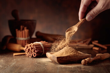 Cinnamon powder is poured into a wooden bowl.