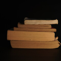old book. a stack of old books on a black and dark background with a little light shining on the sides. reading old books, magic books, history books, mysteries, Halloween