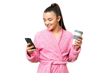 Young woman in a bathrobe over isolated chroma key background holding coffee to take away and a mobile