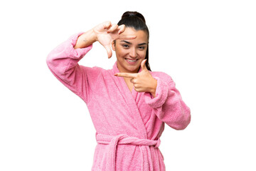 Young woman in a bathrobe over isolated chroma key background focusing face. Framing symbol