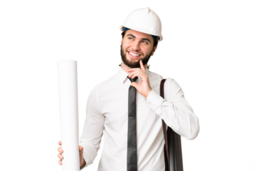 Young architect man with helmet and holding blueprints over isolated chroma key background thinking an idea while looking up