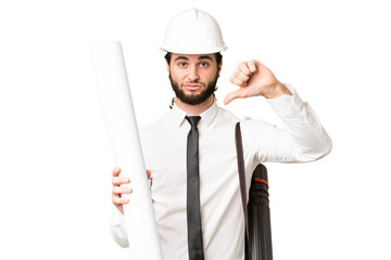Young architect man with helmet and holding blueprints over isolated chroma key background showing thumb down with negative expression