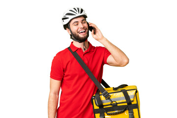 Young delivery man with thermal backpack over isolated chroma key background keeping a conversation with the mobile phone