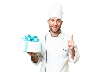 Young handsome blonde man with a big cake over isolated chroma key background pointing up a great idea