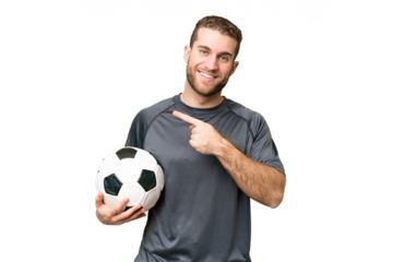 Young handsome blonde man over isolated chroma key background with soccer ball and pointing to the lateral