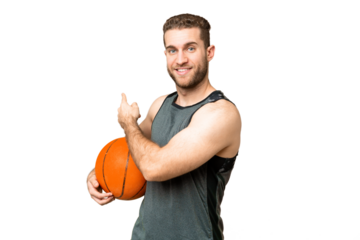 Handsome young man playing basketball over isolated chroma key background pointing back