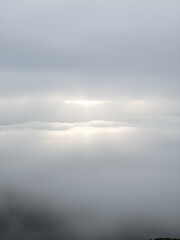 Obraz premium A soft, overcast sky with rolling fog moving across the landscape, creating a mysterious, dreamy atmosphere with light breaking through in soft beams