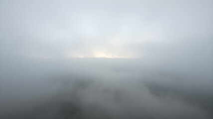 Fototapeta premium A soft, overcast sky with rolling fog moving across the landscape, creating a mysterious, dreamy atmosphere with light breaking through in soft beams