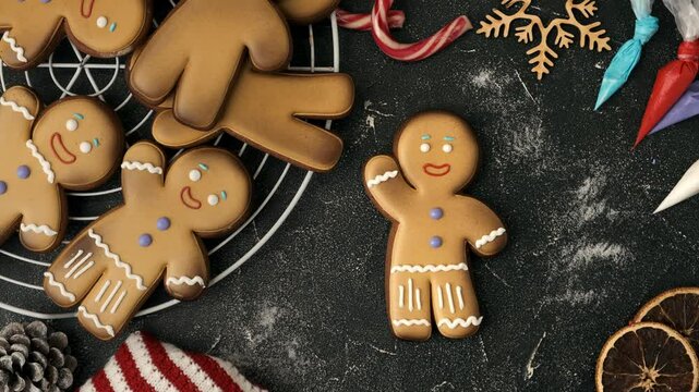 Woman hands hold pastry bag and decorate gingerbread man with white icing. Homemade traditional festive Christmas cookies. Winter holidays background. Merry Christmas and Happy New Year. Close-up