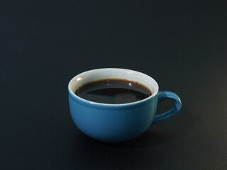 black coffee in a blue cup on a black background