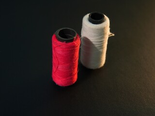 skein of thread on black background. red, white sewing thread. garment industry theme, clothing, convection, tailoring