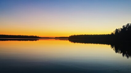 Obraz premium A serene sunset over a calm lake, reflecting vibrant colors in the sky and water.