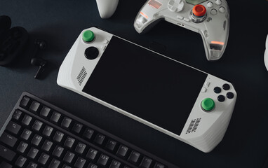 handheld game console concept with mouse, keyboard, joystick, headset, mobile joystick, in ear headphone and mouse pad on black table