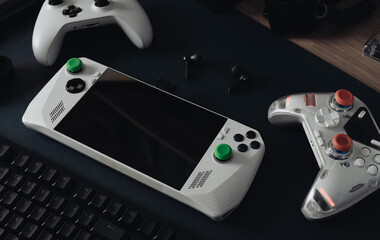 handheld game console concept with mouse, keyboard, joystick, headset, mobile joystick, in ear headphone and mouse pad on black table