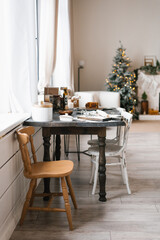 Wooden dining table with two chairs and a Christmas tree in the background