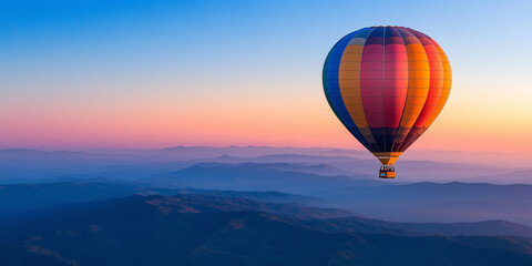 Colorful hot air balloon floating high in the sky over misty mountains at sunrise. Serene aerial view of vibrant balloon drifting above scenic mountain landscape