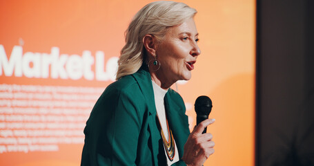 Speaker, mature woman and presentation for financial market or investment seminar for employees. Female person, business conference and discussion for stock, trading and share with microphone in bank