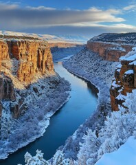 Majestic river valley surrounded by snow-covered cliffs at sunrise