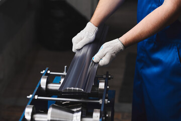 Professional engineer man in blue uniform works in factory. Rolled metal, metal processing and manufacturing of metal fence