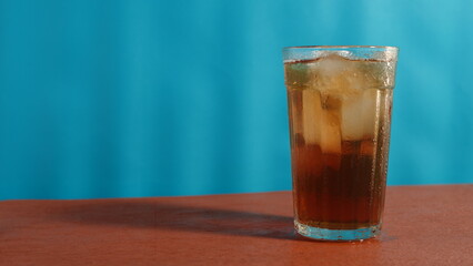 glass of iced tea on wooden table on blue background. drink theme