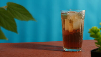 glass of iced tea on wooden table on blue background. drink theme