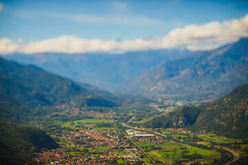 Fototapeta premium Panoramic landscape of the Italian city, photos from a drone, quadcopter, aerial photography. The city, the houses with tiled roofs, the road and the mountains. Layout. A miniature. View of Piedmont, 