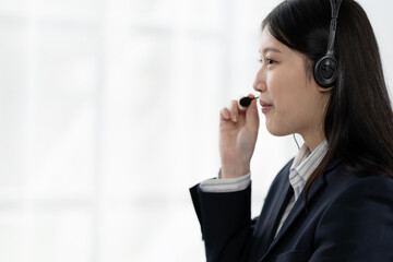 Woman wearing headphones and smiling while working hard in office. Call center. Telemarketing agent. Customer support. Friendly staff in customer support. Wearing headphones with microphone.