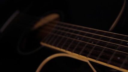 Fototapeta premium guitar background. selective focus. guitar on a dark background with a hint of warm light. guitar strings and fret board. acoustic guitar