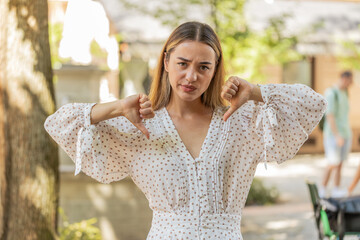 Dislike. Upset Caucasian young woman showing thumbs down sign gesture, expressing discontent,...