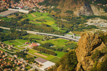 Panoramic landscape of the Italian city, photos from a drone, quadcopter, aerial photography. The city, the houses with tiled roofs, the road and the mountains. Layout. A miniature. View of Piedmont