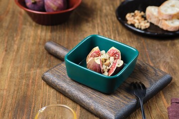 Baked figs stuffed with blue cheese and walnuts in a portioned ceramic form on a wooden background. Fig recipes.