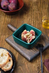 Baked figs stuffed with blue cheese and walnuts in a portioned ceramic form on a wooden background. Fig recipes.