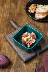 Baked figs stuffed with blue cheese and walnuts in a portioned ceramic form on a wooden background. Fig recipes.