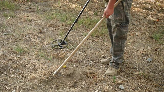 Treasure hunter with a metal detector. The treasure hunter digs up found objects, coins, antiques, shows them on camera and explains their possible value or history.