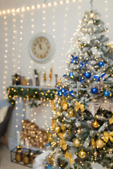 Unfocused shot of fir-tree decorated with blue golden bulbs and bows. Clock over decorative fireplace with logs. Blurry Christmas interior background.