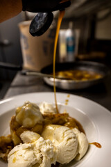 Cheese cake, bananas, caramel dessert. Making dessert behind the scenes. Vanilla Ice cream, whip cream topped on cheese cake, banana sauce topping with caramel on top. 
