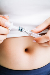 Fat woman holding syringe in front of her belly. Concept of weight loss, medical treatment, diabetes and fertility.