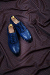 Male blue leather shoes on dark brown suit fabric background. Copy space for logo design, advertising. Natural leather accessories for men