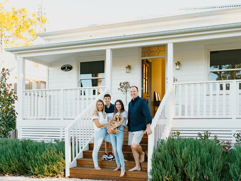 Happy family standing on wooden steps of their porch of Australian home