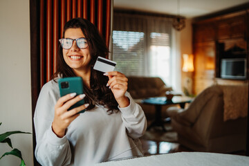 Young caucasian woman shopping online on smartphone using credit card	