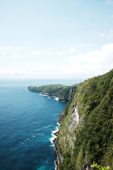 Landscape of wave crashing rocky cliff  and wild on stone mountain at the blue calm sea with sponge on summer with ocean for destination in Bali island at Indonesia