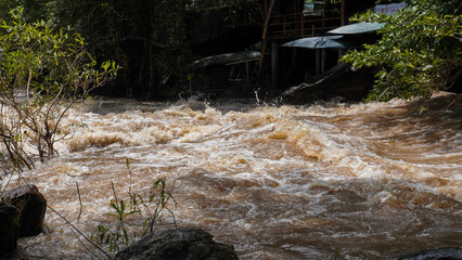A strong current near a waterfall. Floods flowing in mountain rivers after heavy rains. Flash floods, the effects of global warming and the effects of deforestation.