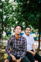 Two Southeast Asian men sitting in a city square, capturing a moment of relaxation and conversation