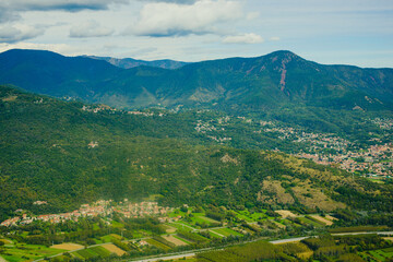 Fototapeta premium Panoramic landscape of the Italian city, photos from a drone, quadcopter, aerial photography. The city, the houses with tiled roofs, the road and the mountains. Layout. A miniature. View of Piedmont, 