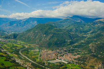 Obraz premium Panoramic landscape of the Italian city, photos from a drone, quadcopter, aerial photography. The city, the houses with tiled roofs, the road and the mountains. Layout. A miniature. View of Piedmont, 