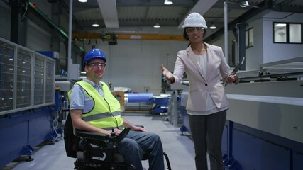 Smiling Indian female factory manager showing the production line to a worker, a man with a disability, and congratulating him on a new job, handheld shot. - Powered by Adobe