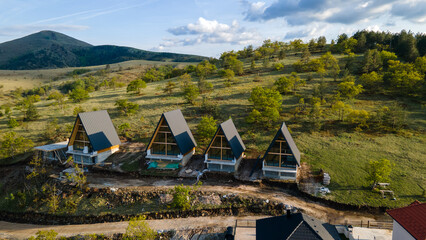 Aerial view of bedful modern houses under construction with triangle roof with flat paths and lawns...